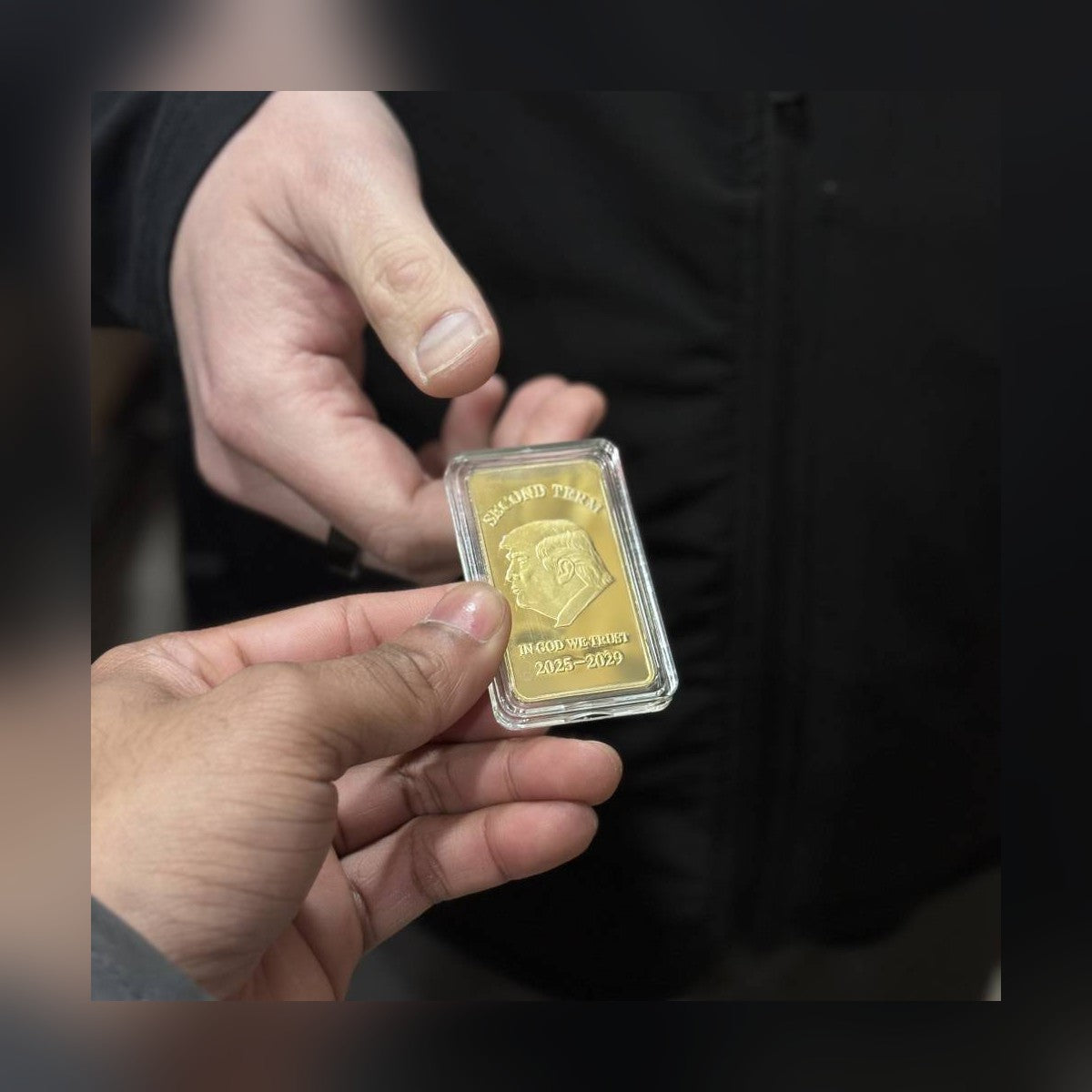 Trump Second Term gold-plated bar in its clear protective capsule, held in hand
