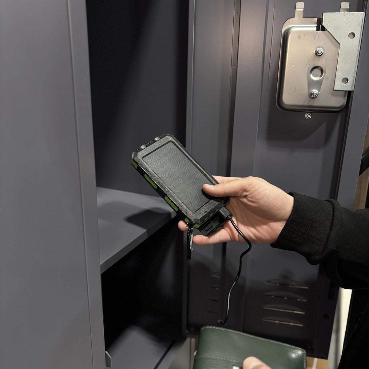 Hand reaching for the Waterproof Solar Charger in a locker cubby