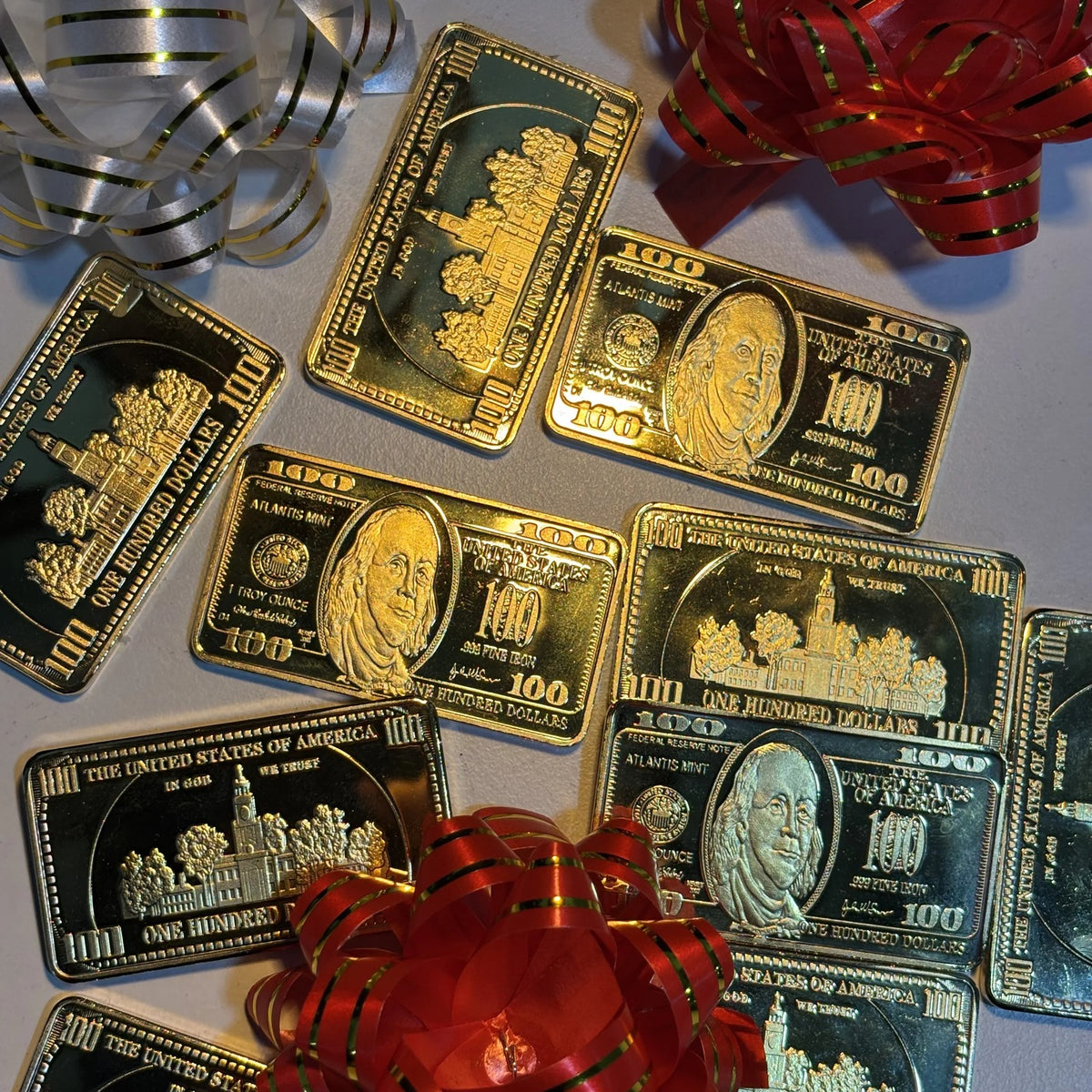 Ben Franklin $100 gold-plated bars scattered among gift bows and ribbon