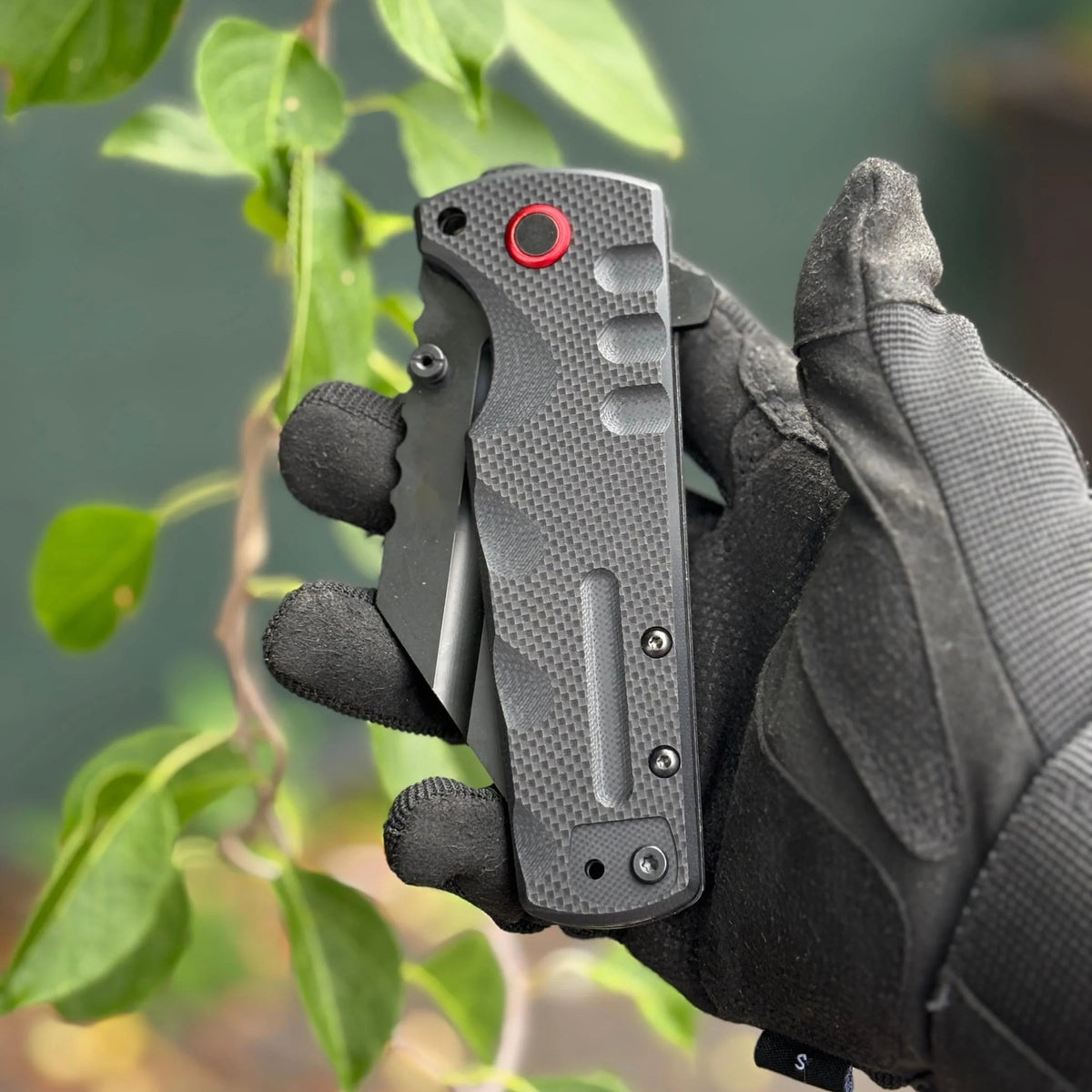 Black Vantage Knife closed in hand showing the solid-black G10 handle and finger grooves