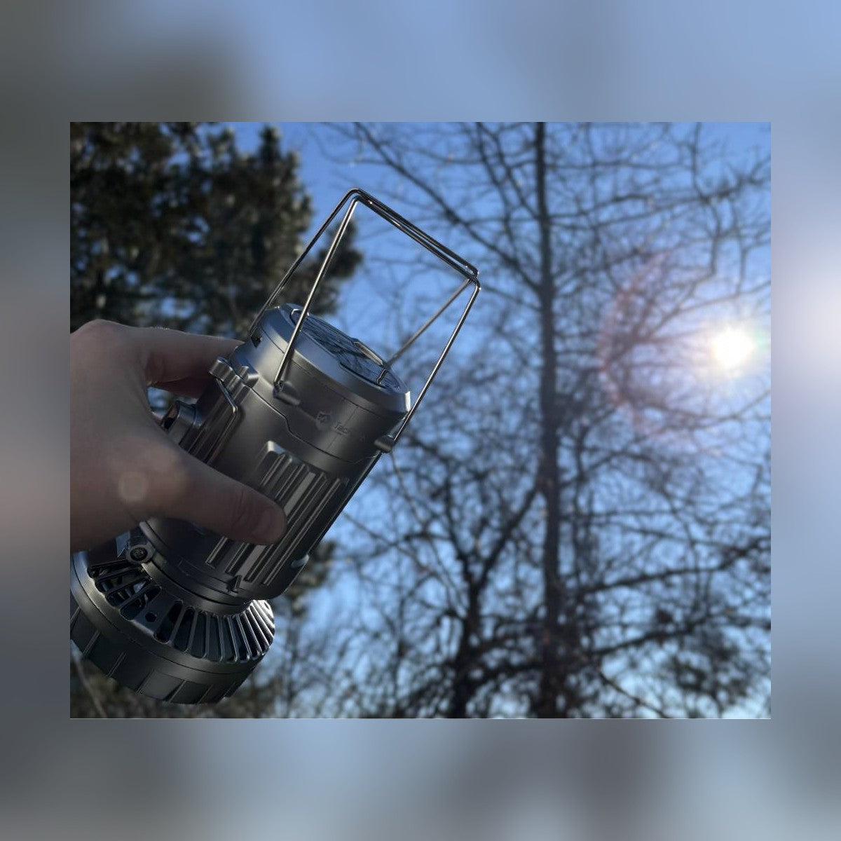 Solar Camping Lantern held in one hand by its body against the sky