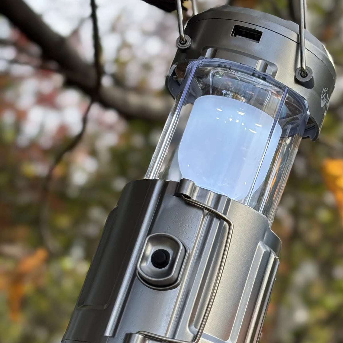 Solar Camping Lantern hanging from a branch in the fall, close view of the light chamber and fan base