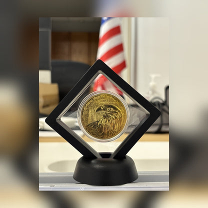CoinSeal Floating Coin Display holding an eagle coin on a desk with a flag behind