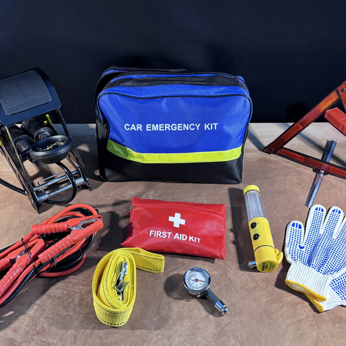 Emergency Car Kit bag with foot pump, warning triangle, first aid pouch, cables and gloves on a table