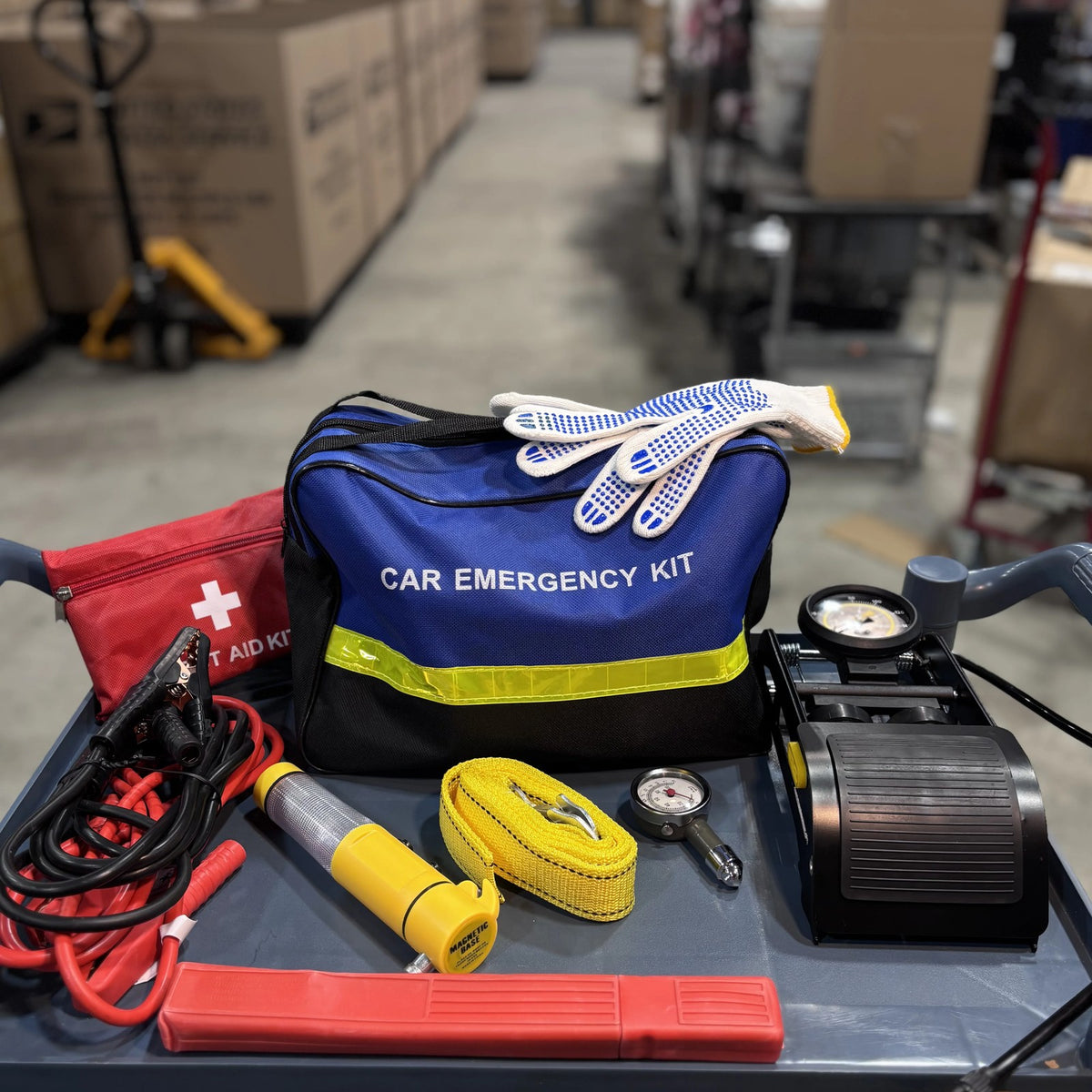 Emergency Car Kit packed with gloves on top, foot pump and tow strap on a shop cart