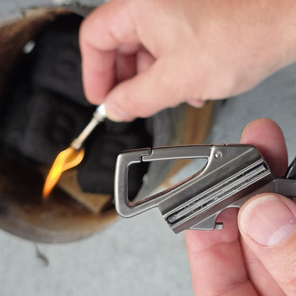 Hands lighting the FireStrike metal match along the flint strip over a fire can