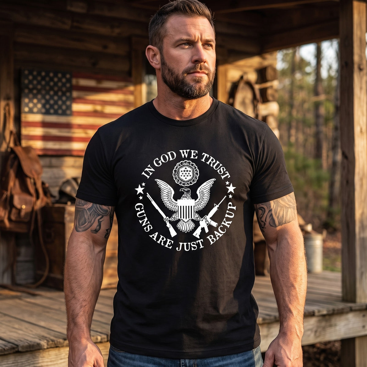 Guns Are Just Backup T-Shirt worn on a cabin porch with an American flag