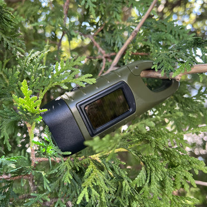 Hand Crank Flashlight clipped by its carabiner to an evergreen branch
