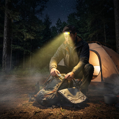 Camper wearing the Headlamp while packing gear outside a tent at night