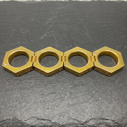 Knuckle Ring opened flat into a row of four hexagonal rings on slate