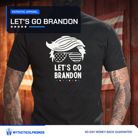 Let's Go Brandon T-Shirt worn by a man in front of a red barn wall with an American flag