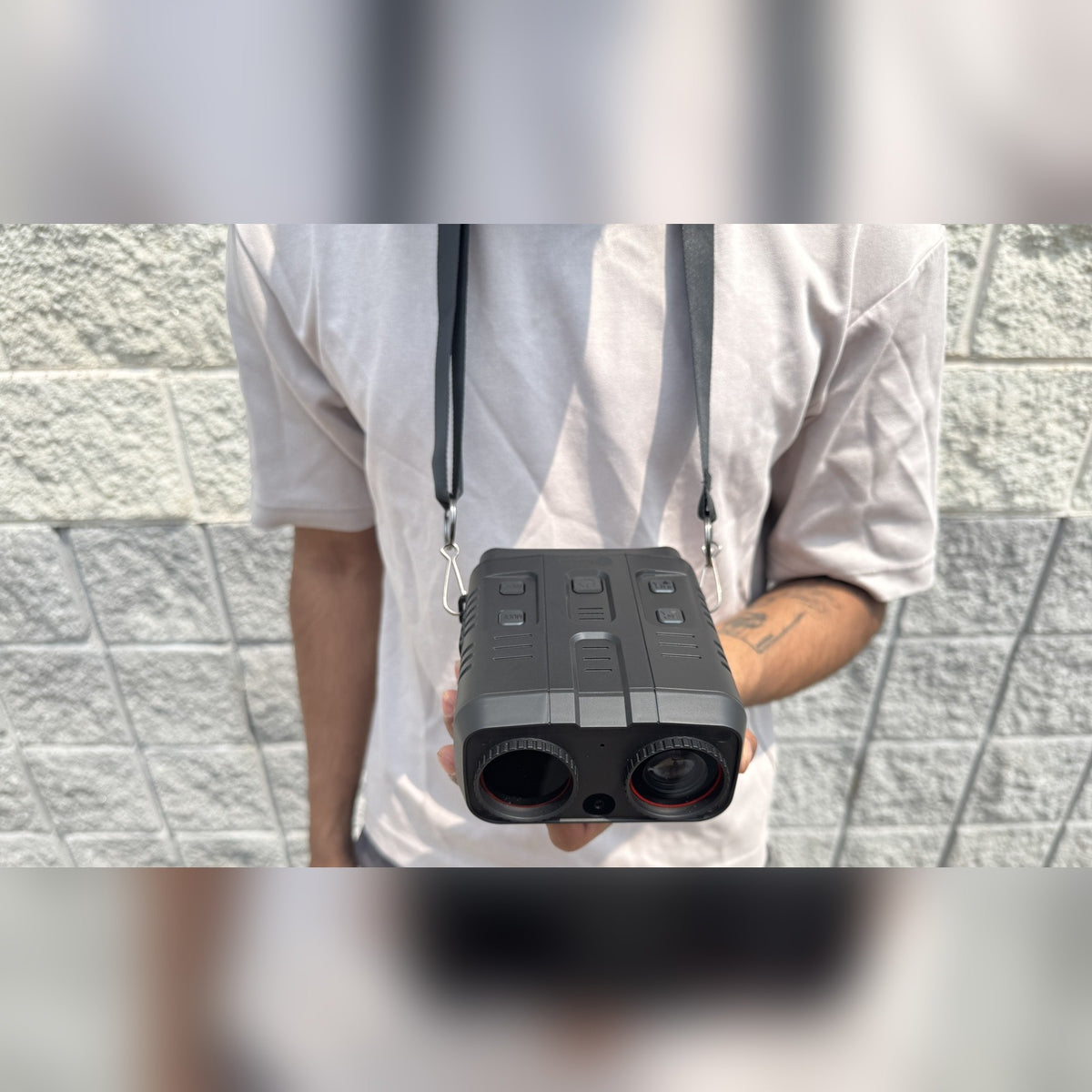 Night Vision Goggles hanging from a neck strap, held at chest height