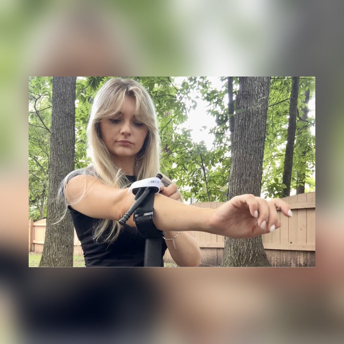 Woman practicing with the One-Arm Tourniquet Kit tourniquet on her forearm outdoors