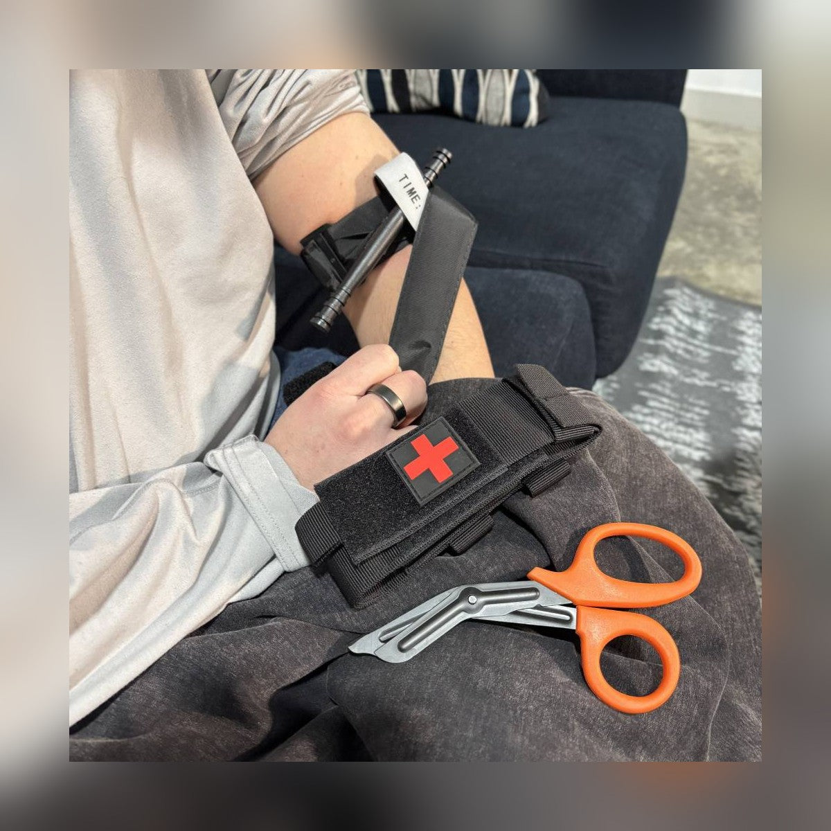 One-Arm Tourniquet Kit tourniquet on an upper arm with the holster and shears on the lap
