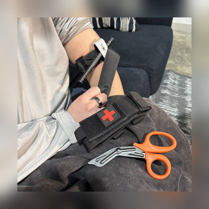 One-Arm Tourniquet Kit tourniquet on an upper arm with the holster and shears on the lap