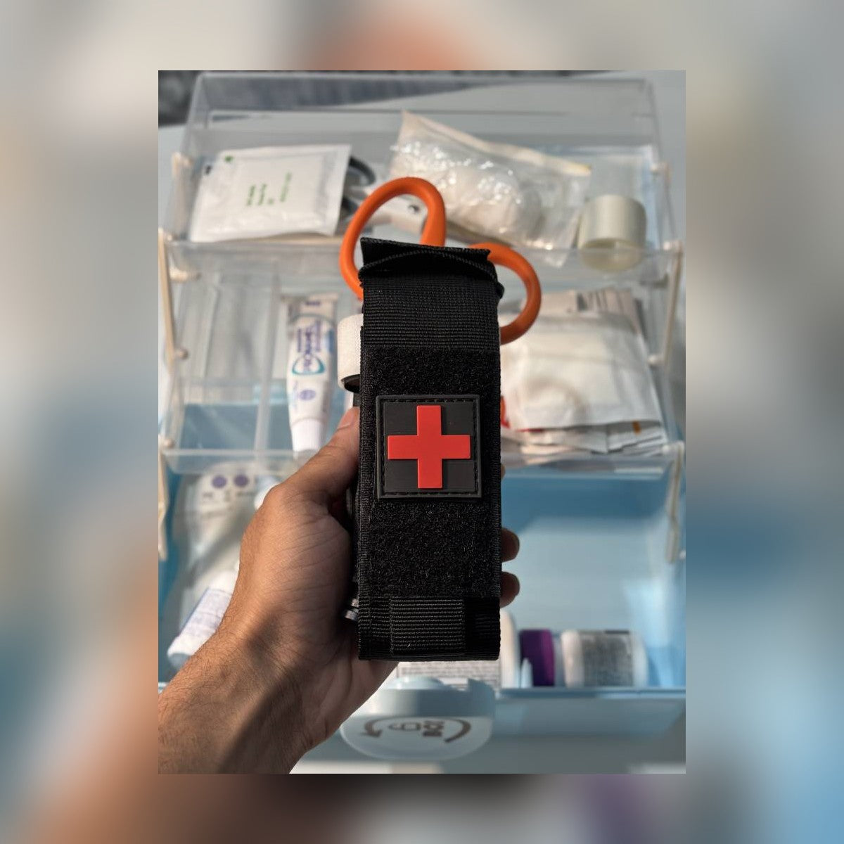 One-Arm Tourniquet Kit holster held over a home first aid box