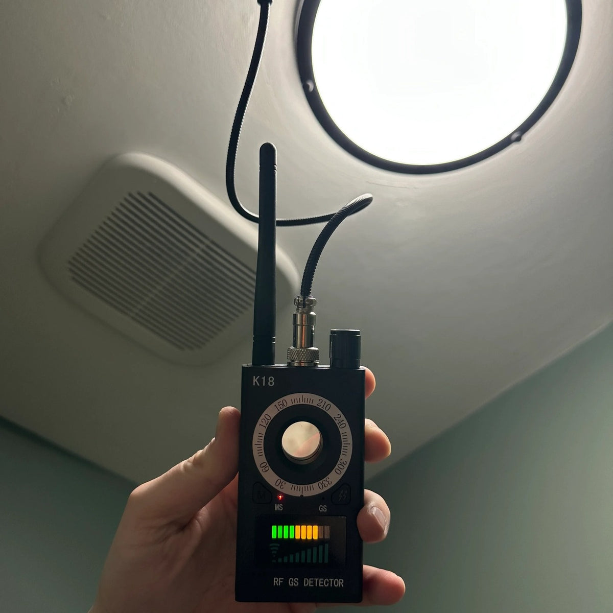 Spy Bug Detector held up to a ceiling light and vent