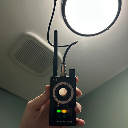 Spy Bug Detector held up to a ceiling light and vent