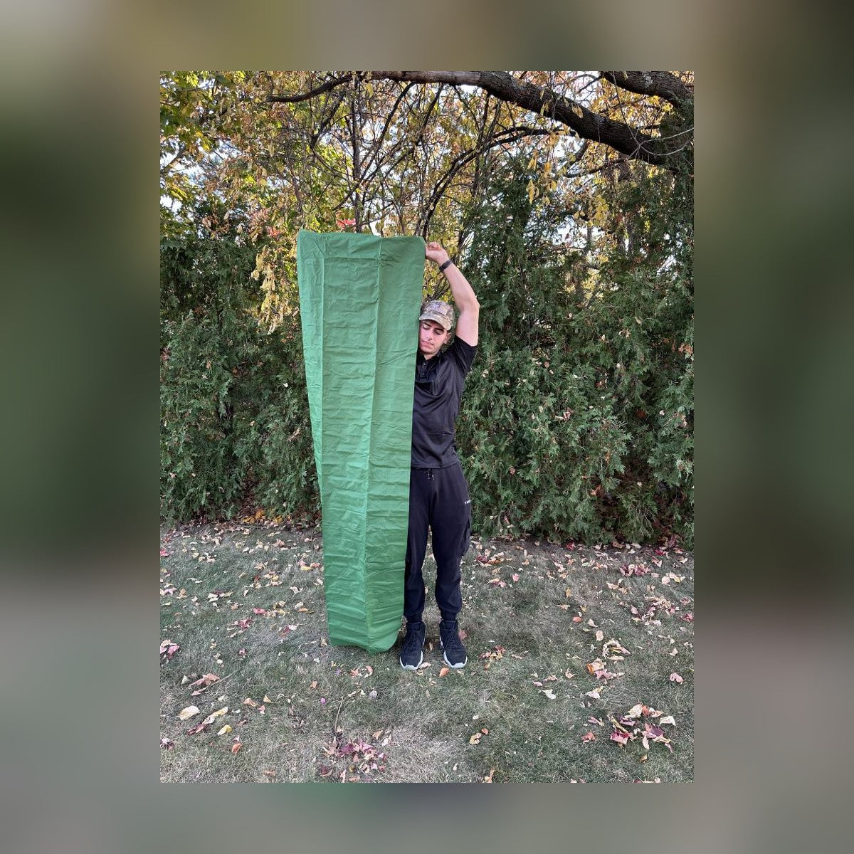 Man holding the Survival Mattress upright to show its full length against his height