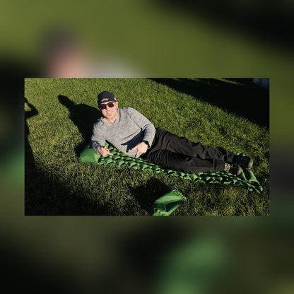 Man resting on the Survival Mattress on the grass in the sun