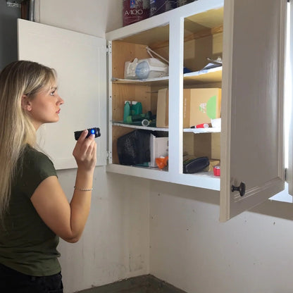 Woman using the Tactical Flashlight to look into a garage cupboard