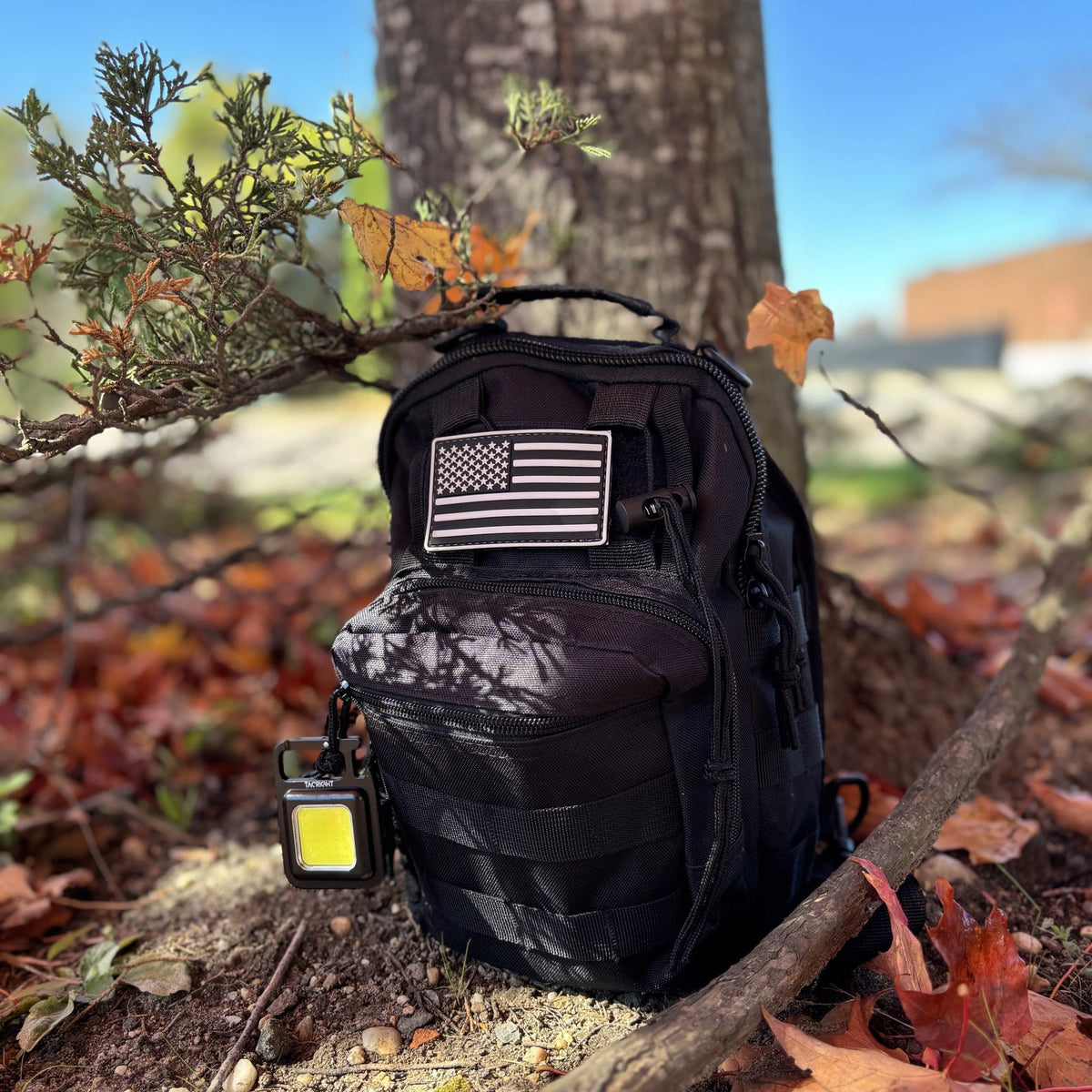 Tactical Shoulder Bag resting against a tree in fall leaves
