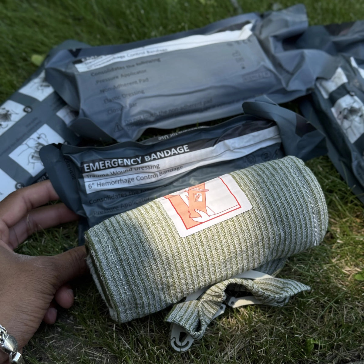 Trauma Bandage rolled with its pad label beside the sealed pack outdoors