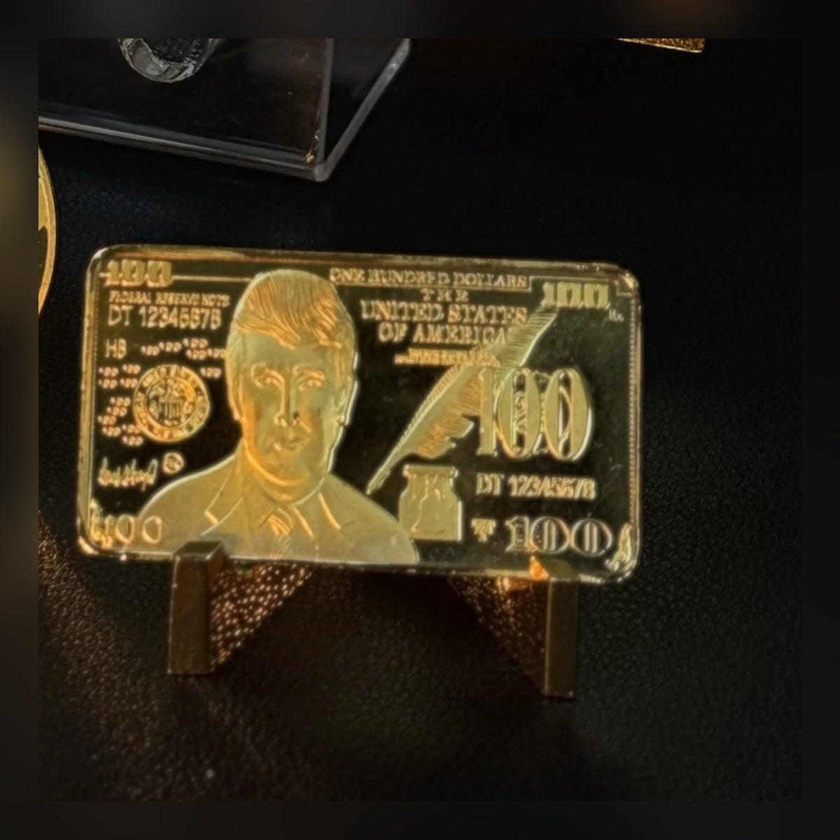 Trump $100 portrait gold-plated bar on a small stand on a desk