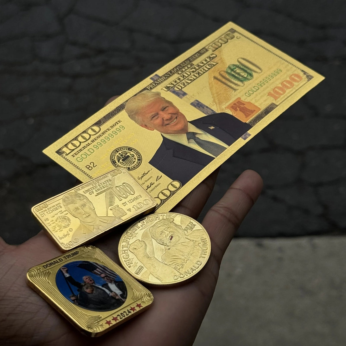 Trump $1000 gold foil novelty bill across an open palm, shown with other keepsakes sold separately