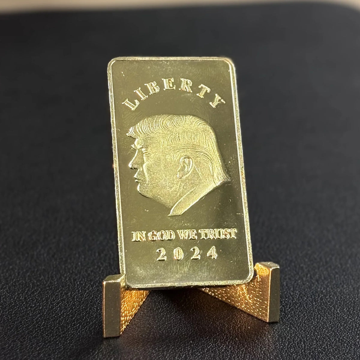 Trump Liberty 2024 gold-plated bar standing on a small gold stand on a black desk