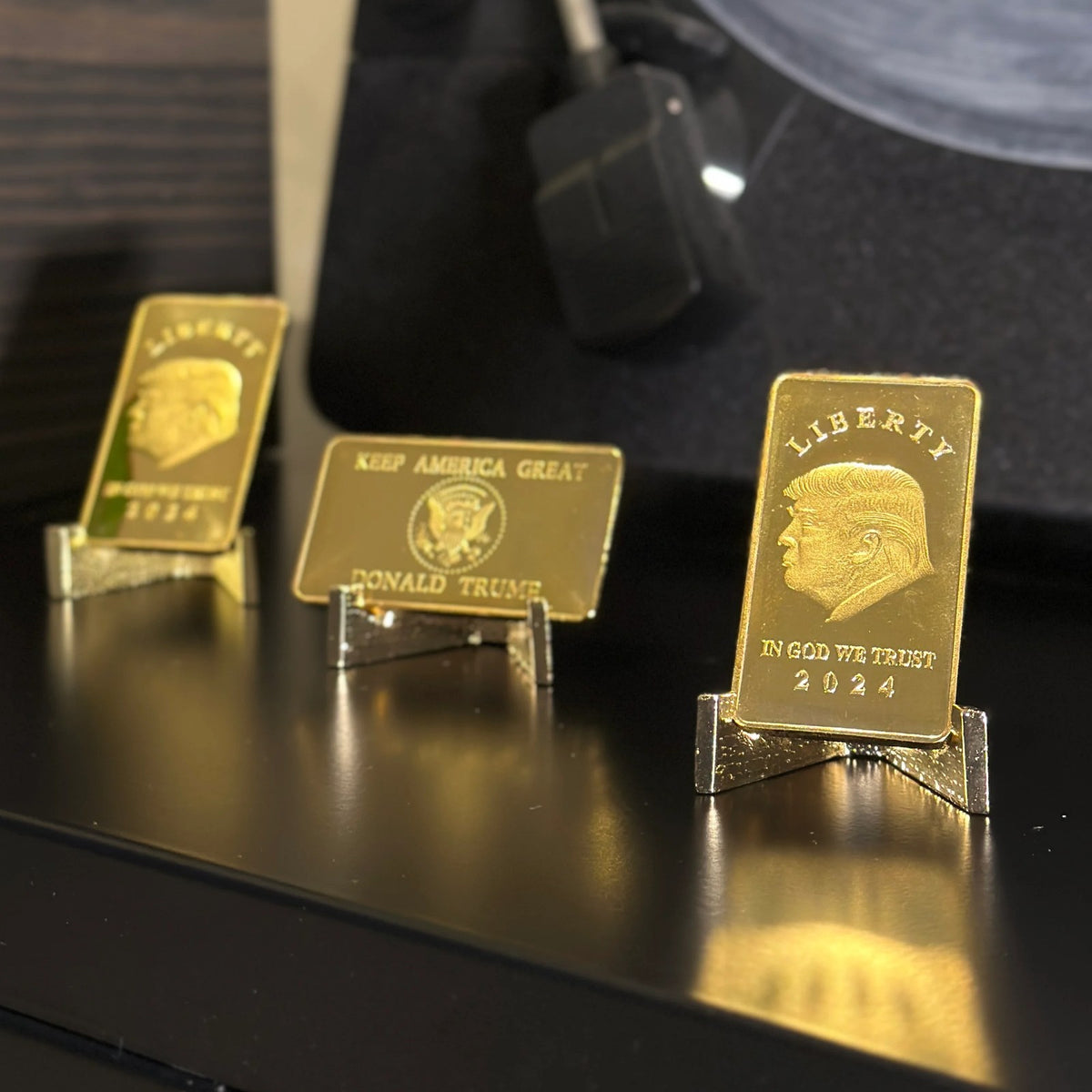 Trump Liberty 2024 gold-plated bars on a black shelf, fronts and Keep America Great reverse shown