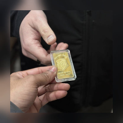 Trump Second Term gold-plated bar in its clear protective capsule, held in hand