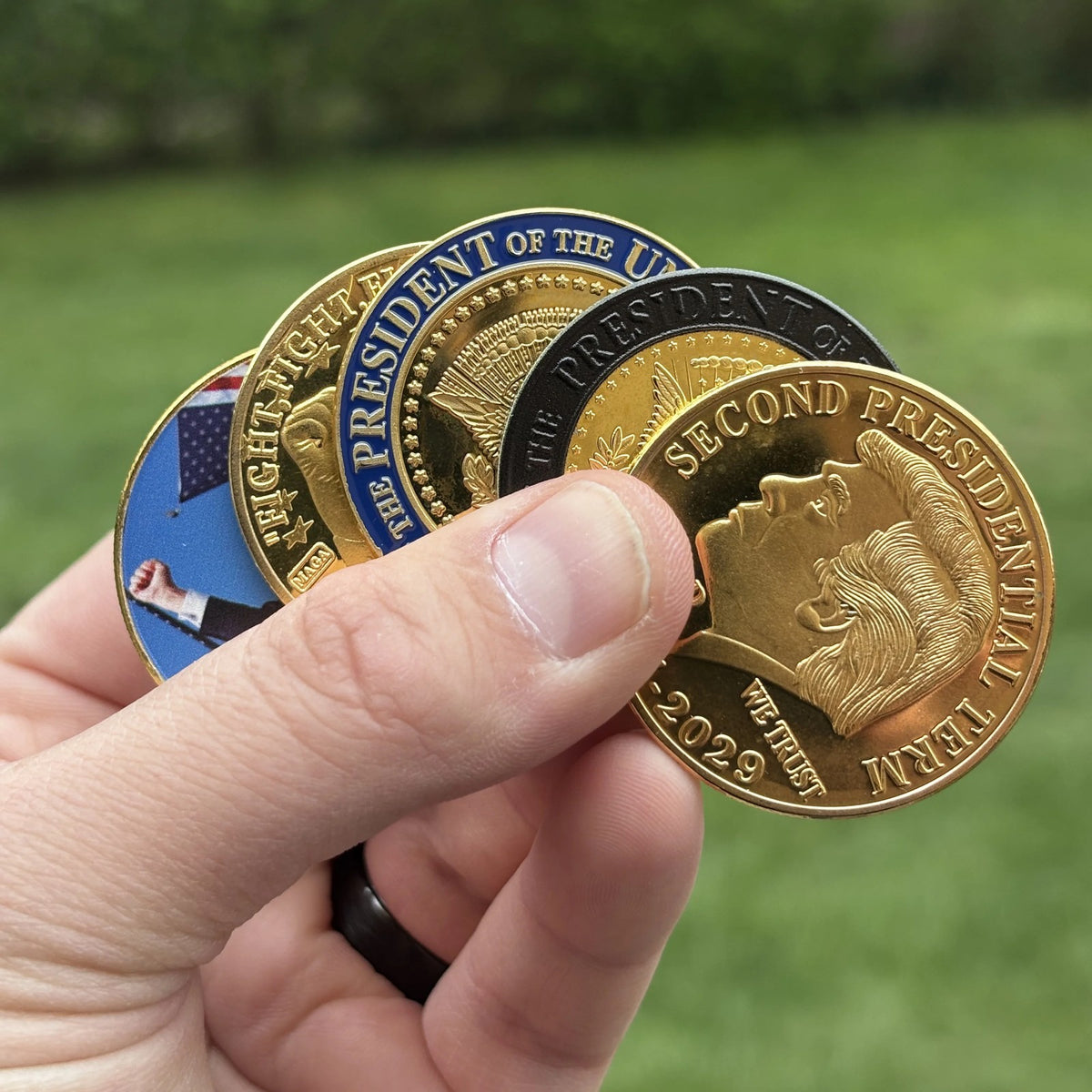 Trump Second Term Coin held in hand outdoors with other coins from our line (sold separately)