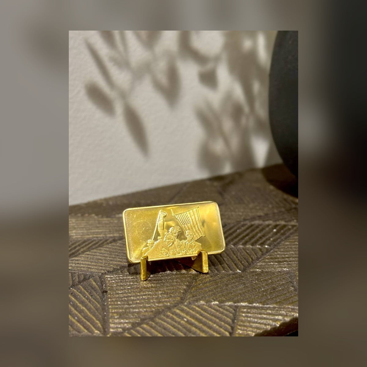 Trump July 13 commemorative gold-plated bar on a stand on a textured shelf