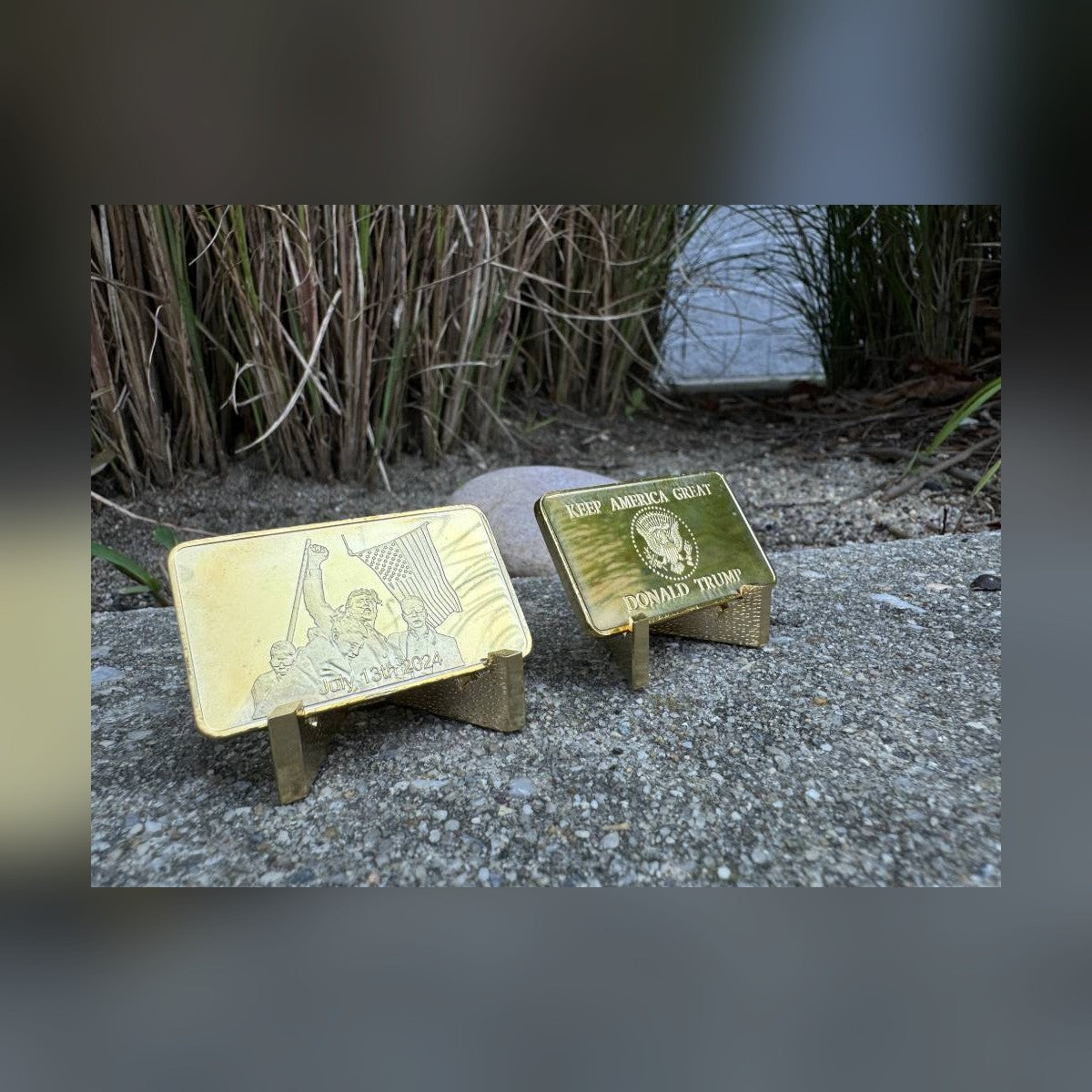 Trump July 13 commemorative bars on stands outdoors, front and Keep America Great reverse