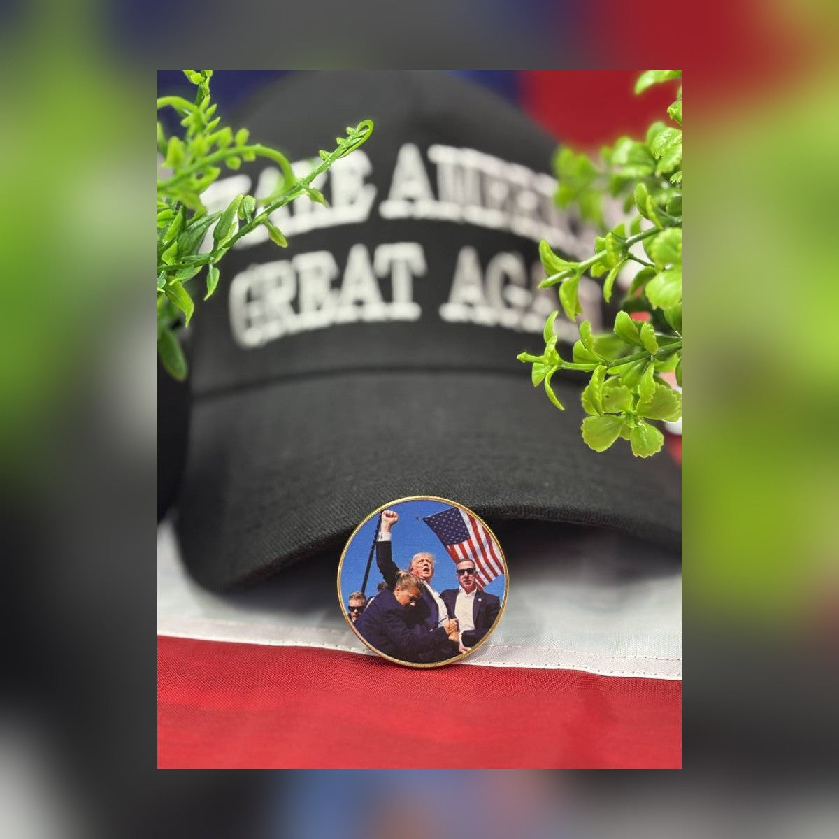 Trump July 13 Coin leaning against a black Make America Great Again cap