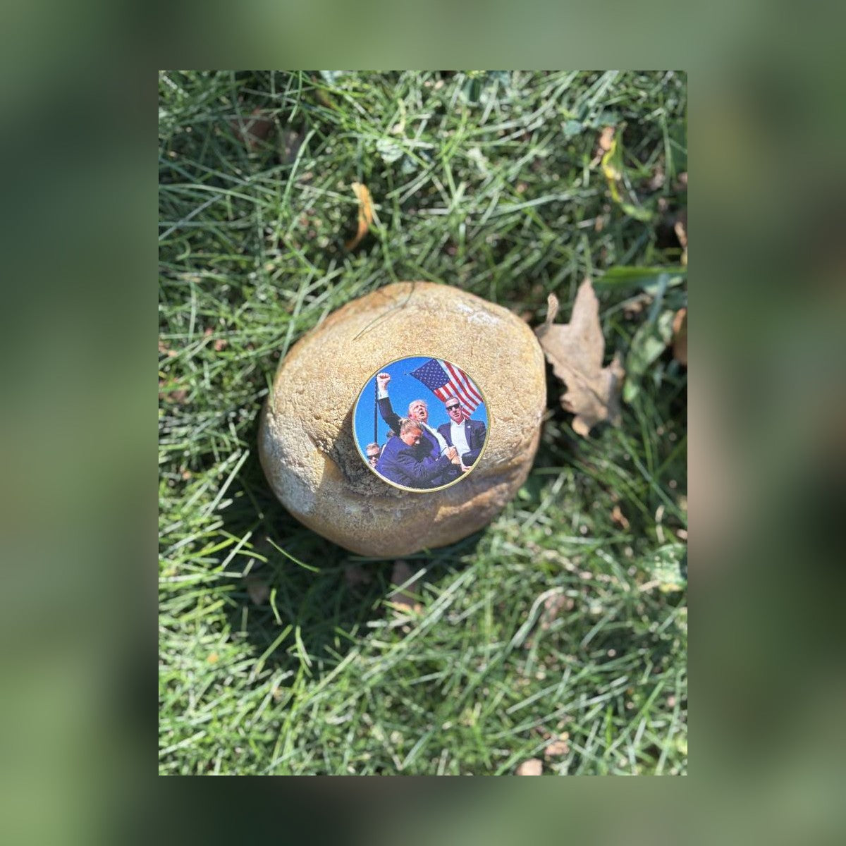 Trump July 13 Coin resting on a stone in the grass