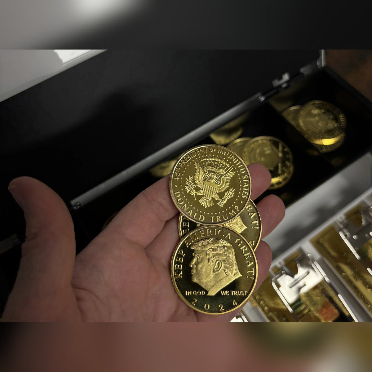 Trump 2024 coins, front and back, held in hand