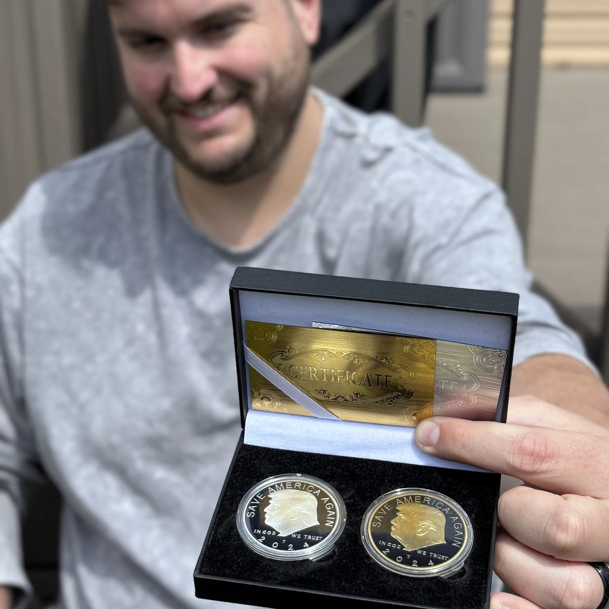 Smiling man holding out the open Trump gold and silver coin case