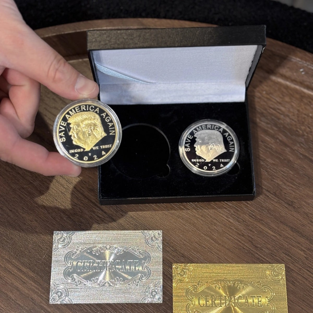Trump gold and silver coin case open on a wooden table with one coin lifted out