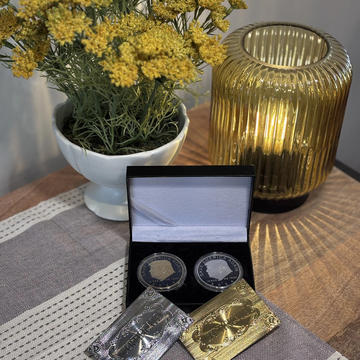 Trump gold and silver coin case on a table at home beside flowers