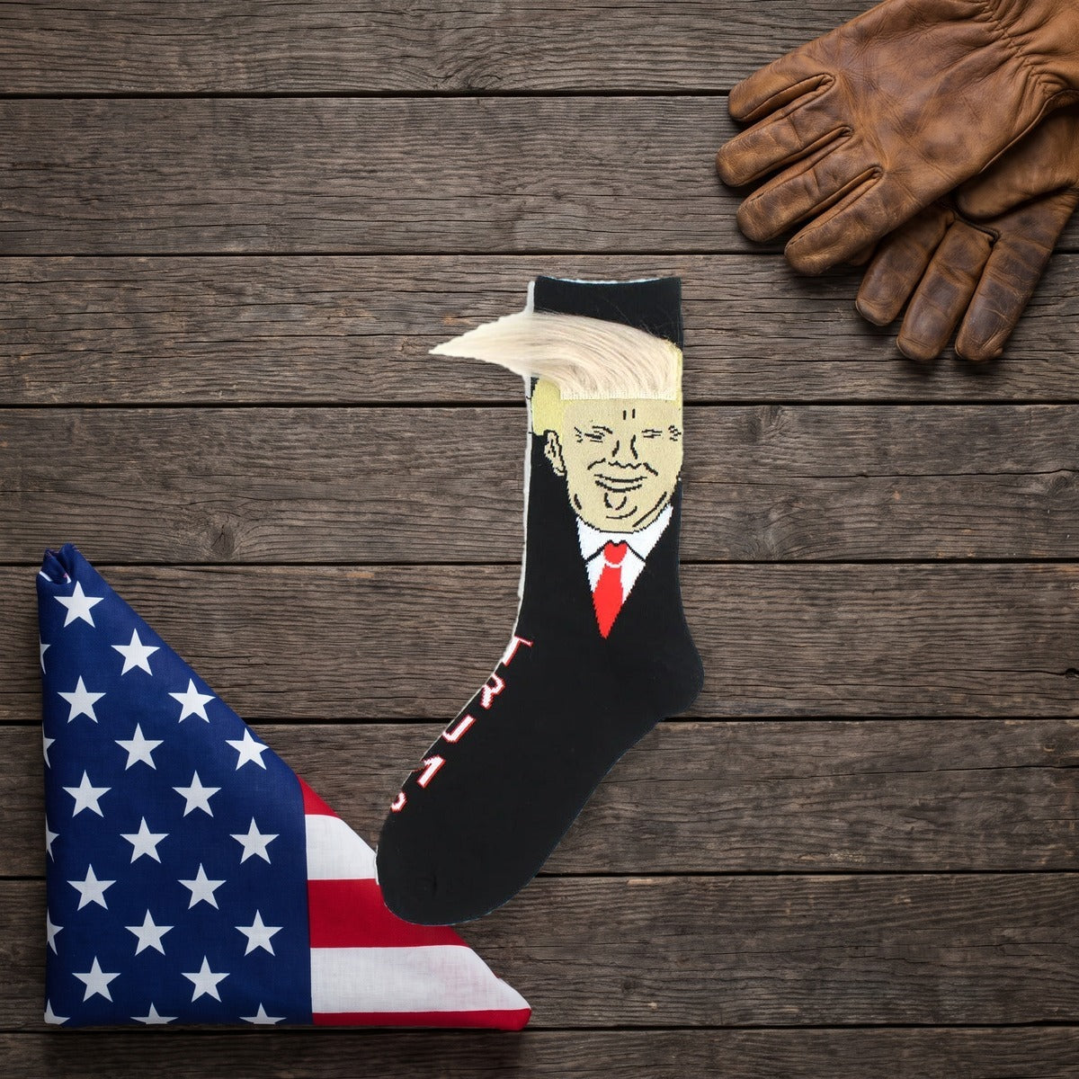 Trump Hair Socks on a dark wood table beside a folded flag