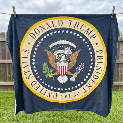 Trump Presidential Blanket hanging on a clothesline, straight-on view of the full seal-style design