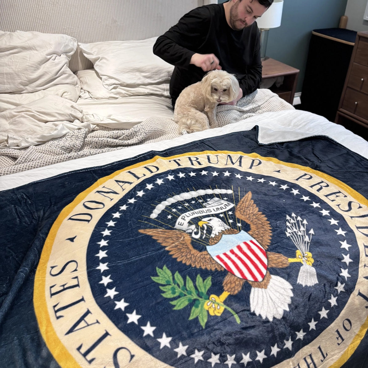 Trump Presidential Blanket spread on a bed with a small dog