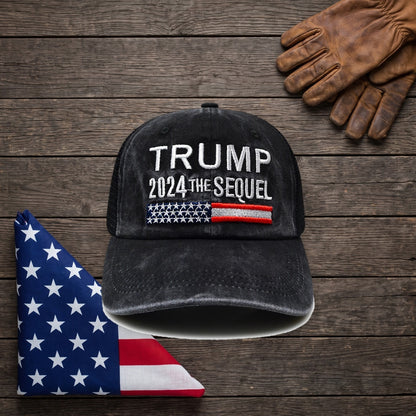 Trump 2024 The Sequel Hat on a dark wood table beside a folded American flag