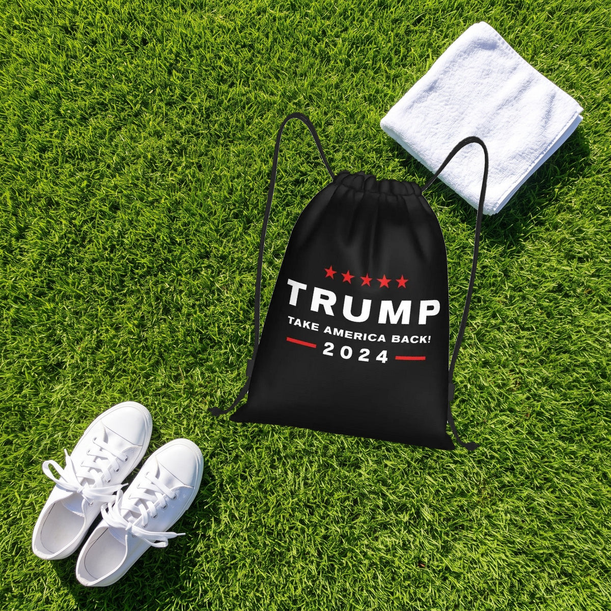 Trump Drawstring Bag on a green lawn next to sneakers and a towel