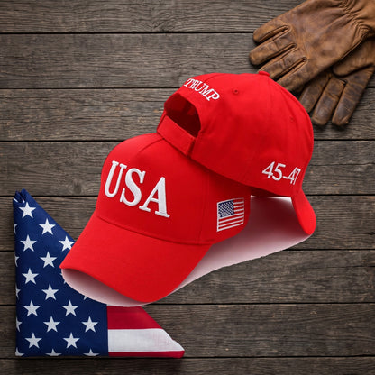Red Trump USA Hat on a dark wood table beside a folded American flag