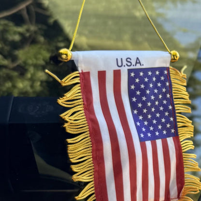 USA Flag Mini Pennant close-up hanging in a car window in bright sun
